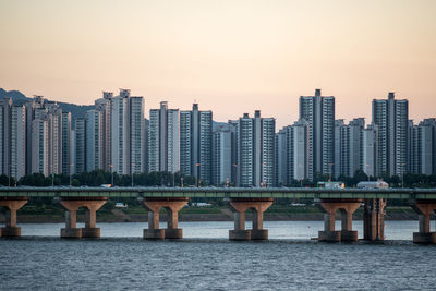 Bridge over river by buildings against sky in city