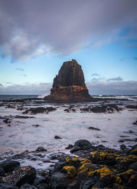 Rock formation on beach against sky