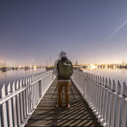 Rear view of man standing on pier against sky