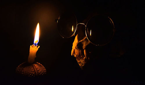 Close-up of burning candle against black background