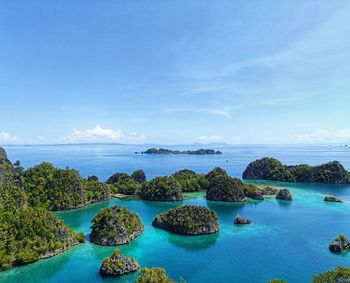 Scenic view of group of islands over the clear blue sea against sky at raja ampat, papua, indonesia