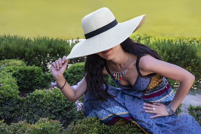 Midsection of woman wearing hat sitting on field