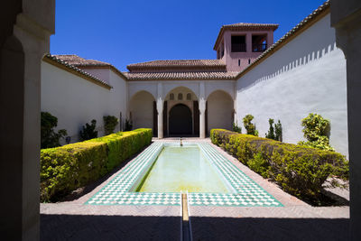 View of swimming pool by building against clear blue sky