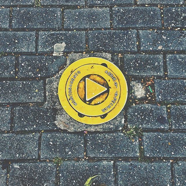 communication, text, yellow, street, western script, number, guidance, close-up, sign, high angle view, no people, wall - building feature, symbol, capital letter, arrow symbol, geometric shape, outdoors, day, information sign, manhole