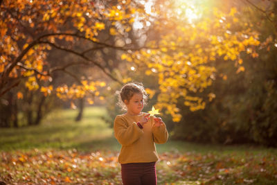 Close-up of girl with autumn leaves on land