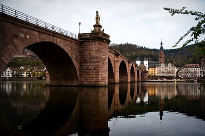 Arch bridge over river against cloudy sky