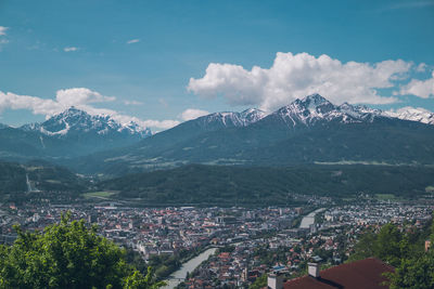 Aerial view of city by mountains against sky