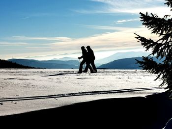 Silhouette people on snowcapped mountain against sky