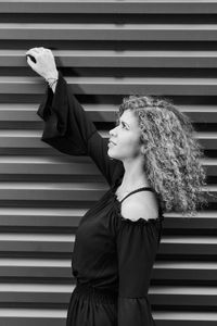 Side view of young woman standing against staircase