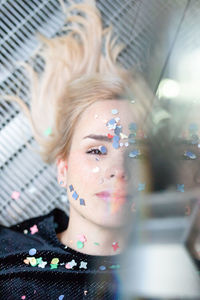 Portrait of woman with confetti on face lying on floor