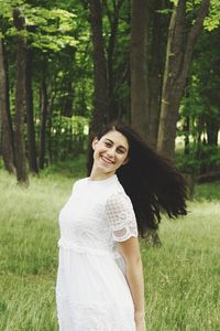 Portrait of cheerful woman standing on grassy field