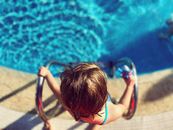 High angle view of girl entering swimming pool