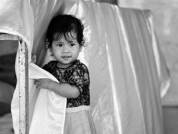 Portrait of cute girl standing against curtain