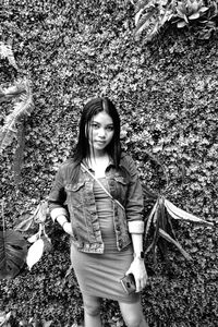 Portrait of smiling young woman standing against plants