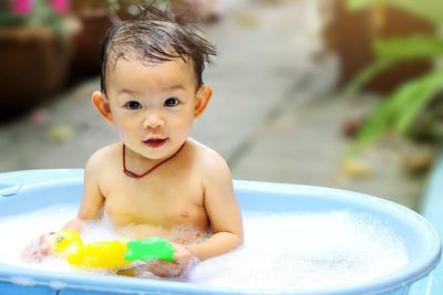 Portrait of cute baby girl holding toy in bathtub