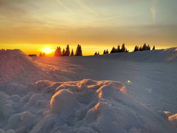 Scenic view of snow covered landscape against orange sky