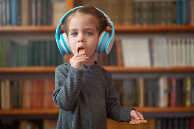 Cute girl wearing headphones in library