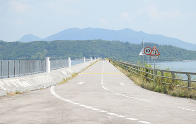 Road sign by mountains against sky