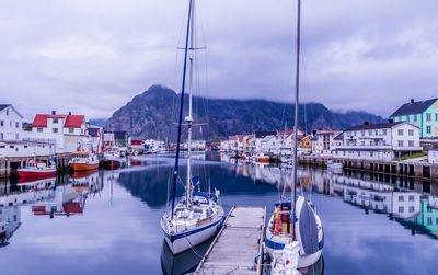 Boats moored at harbor against sky