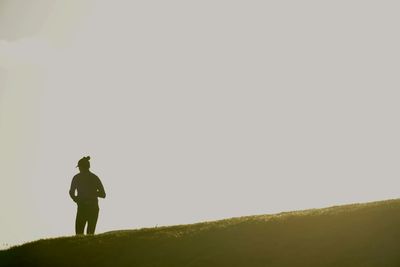 Rear view of man standing on field against sky