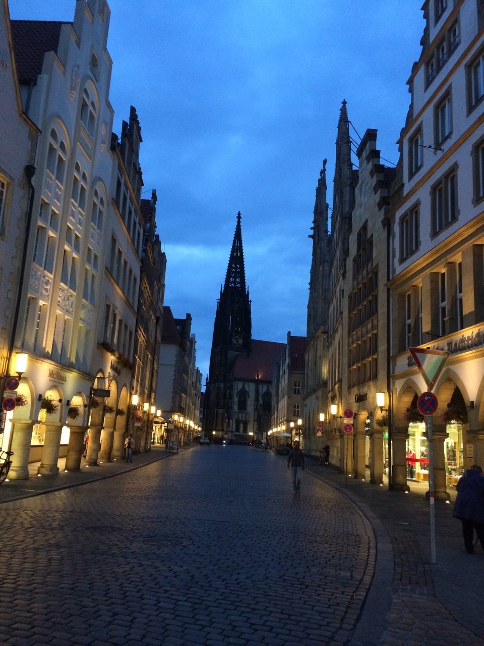 building exterior, architecture, built structure, illuminated, city, the way forward, street, sky, street light, cobblestone, diminishing perspective, night, lighting equipment, building, city street, city life, incidental people, residential building, vanishing point, outdoors