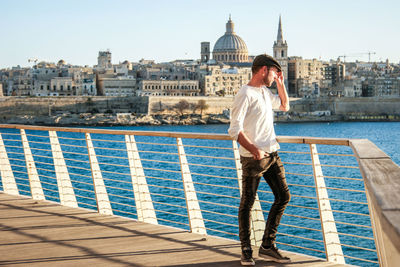 Full length of man standing on railing on footbridge over river