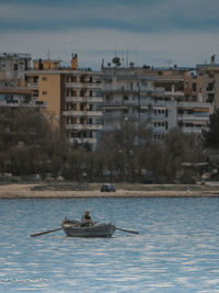 People on river against buildings in city