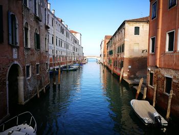 Canal amidst buildings against clear sky