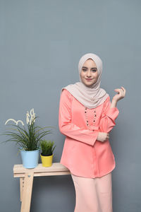 Portrait of woman standing against pink background