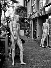 Statue of man standing by sculpture in city