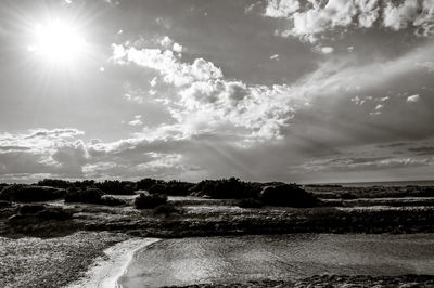 Scenic view of bright sun over land against sky