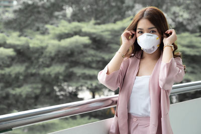 Portrait of beautiful woman standing against railing