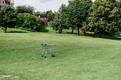 Shopping trolley in park against sky