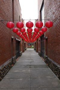 Red lanterns on footpath by building