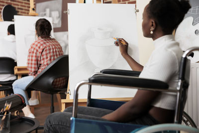 Side view of woman using digital tablet while sitting at gym