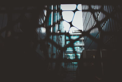 Silhouette buildings against sky seen through window