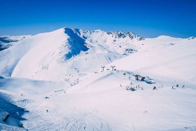 Aerial view of snow covered landscape against blue sky