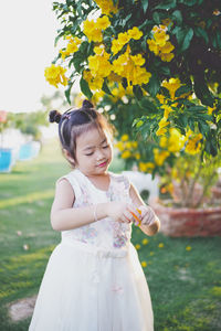 Girl picking yellow flowers on branches at park