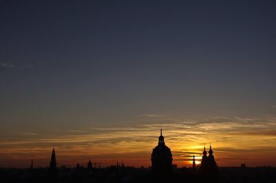 Silhouette of building against cloudy sky at sunset