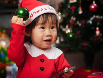 Cute girl wearing costume standing by christmas tree at home
