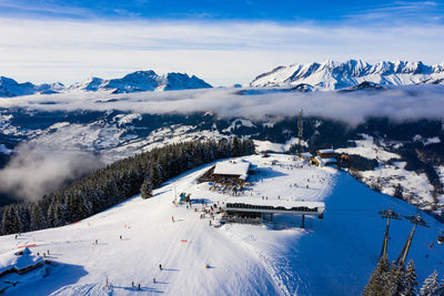 Aerial view of people skiing on snow covered mountain against sky