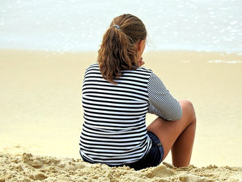 Rear view of woman sitting on beach