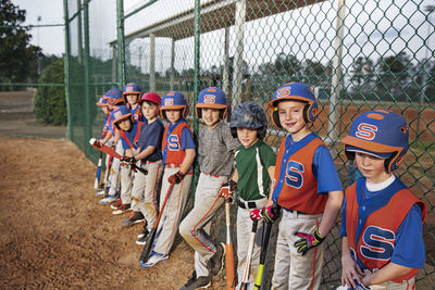 Baseball team standing by chainlink fence on field