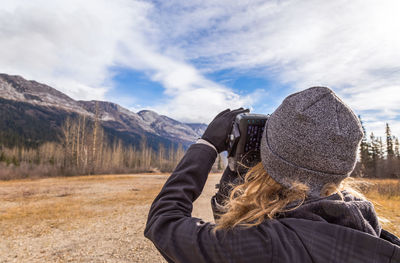 Rear view of woman photographing against sky