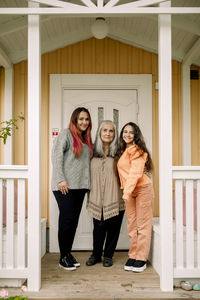 Portrait of smiling senior woman with daughter and granddaughter standing at porch