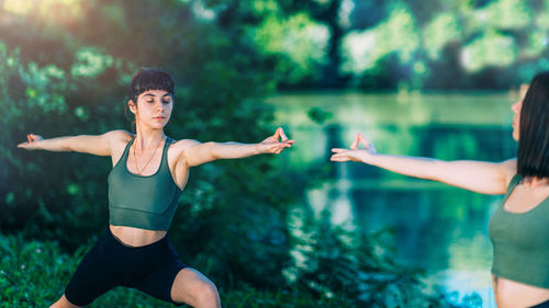 Yoga women by the lake. warrior pose