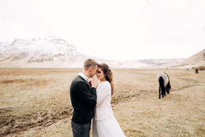 Couple standing on land against sky