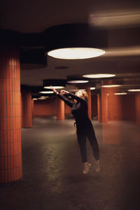 Woman jumping in illuminated garage