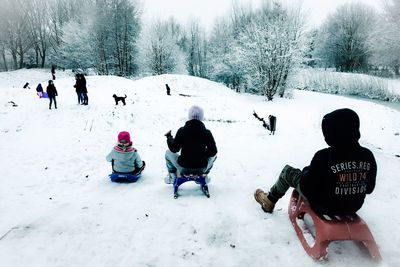 Rear view of kids tobogganing on snow