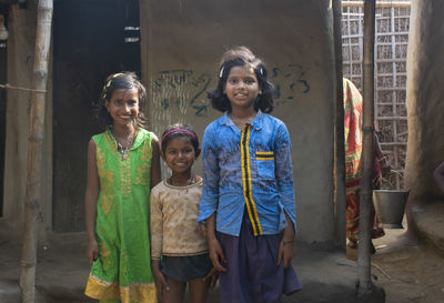 Portrait of happy young children standing against the mud wall in rural area of india